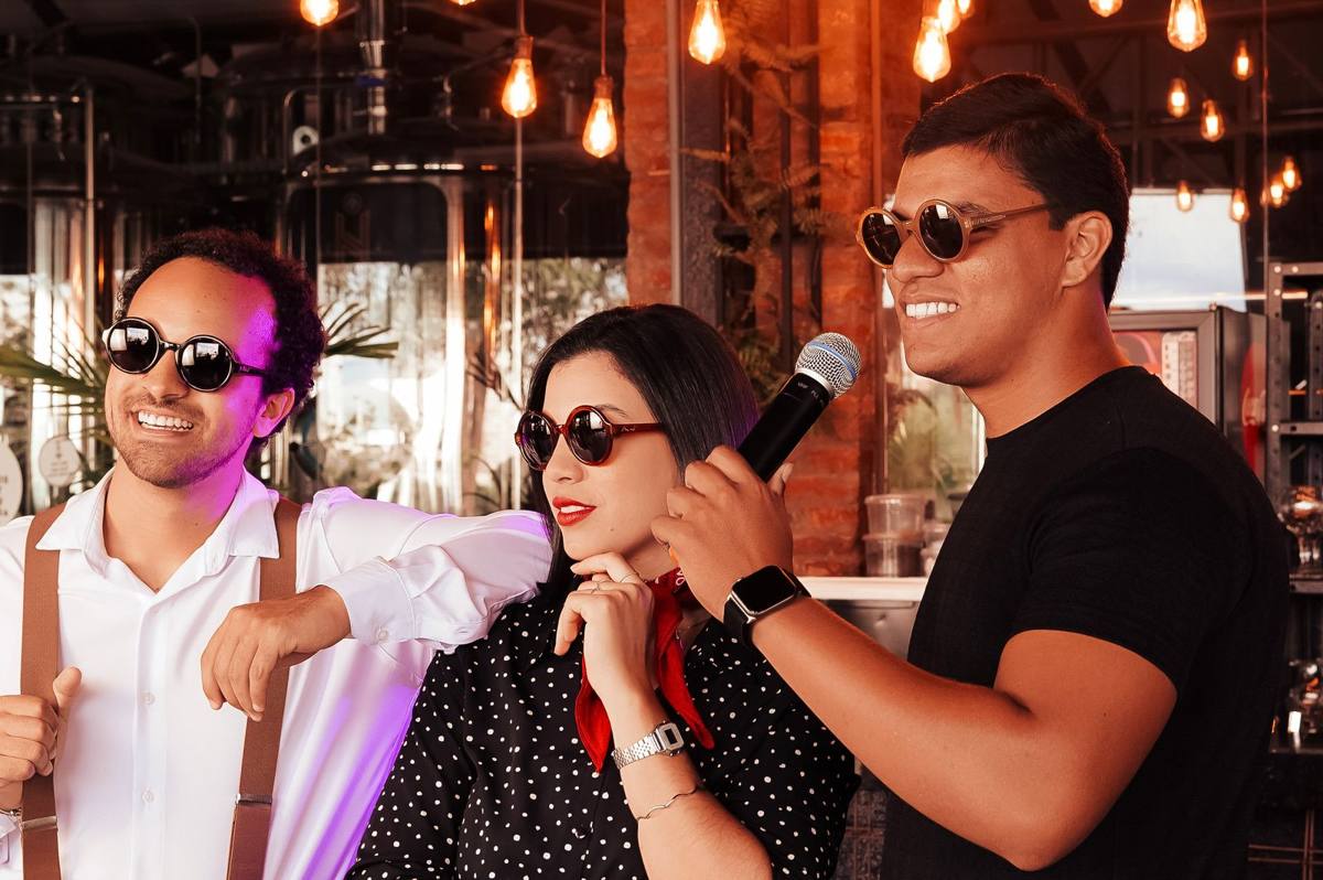 Tres amigos cantando con un micrófono