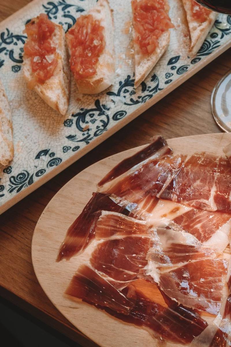 Jamón cortado y pan con tomate sobre tabla